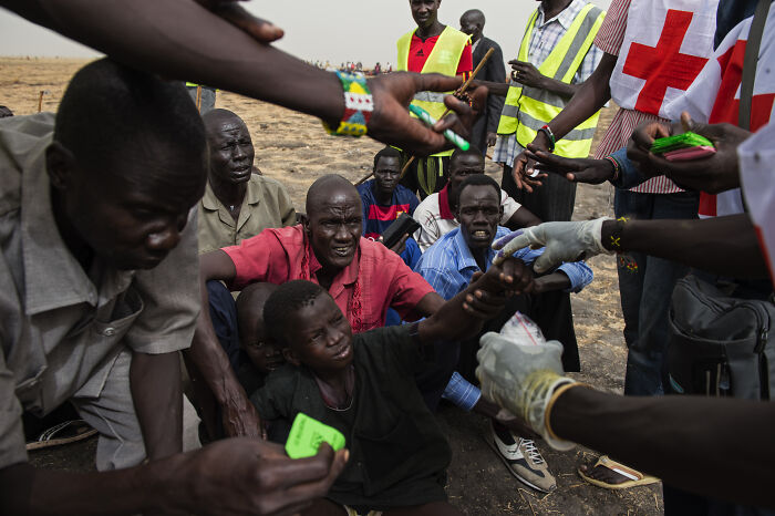 A group of African migrants receiving aid from relief workers in a tense situation near conflict zones.