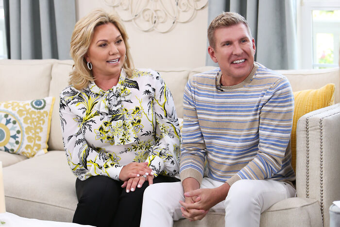 A woman and man sitting on a couch, discussing reality TV parents pardoned for bank fraud involving $36 million.