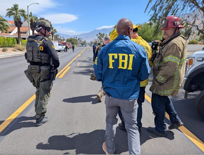 FBI and emergency responders on scene outside IVF clinic after reported bombing incident in urban area with clear skies.
