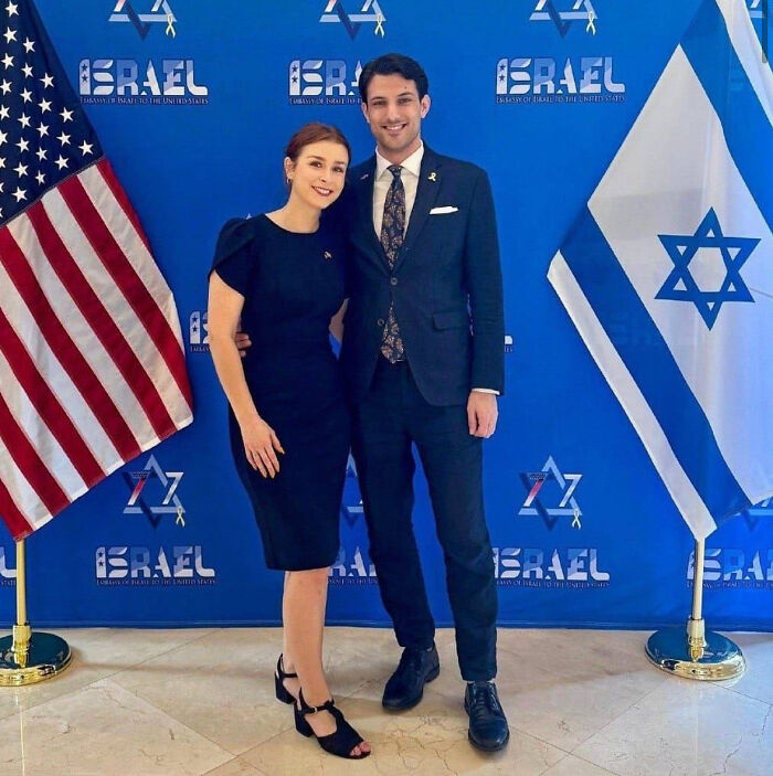 Couple posing at Israeli Embassy with Israeli and American flags, linked to FBI suspect in flamethrower protest attack.