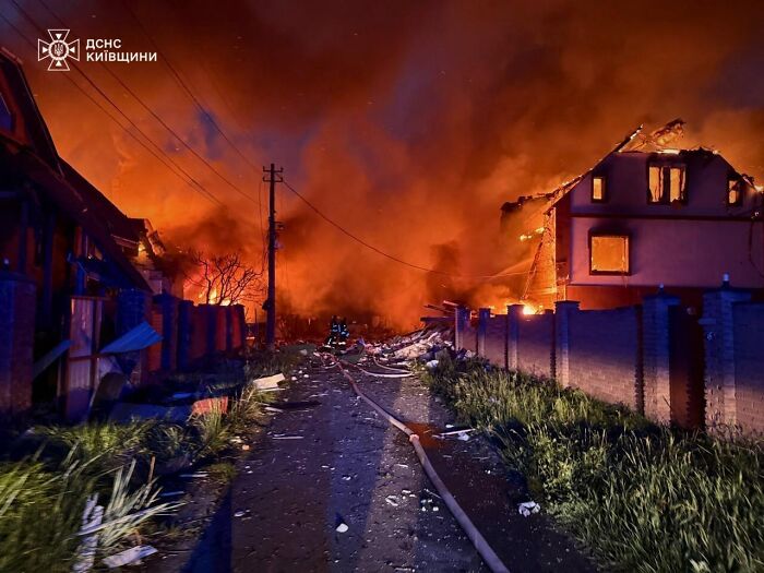 Fire and destruction in a residential area amid largest Russian attack on Ukraine with emergency responders at the scene.