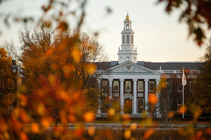 Harvard University building seen through autumn trees, related to biographer uncovering Donald Trump's bitterness.