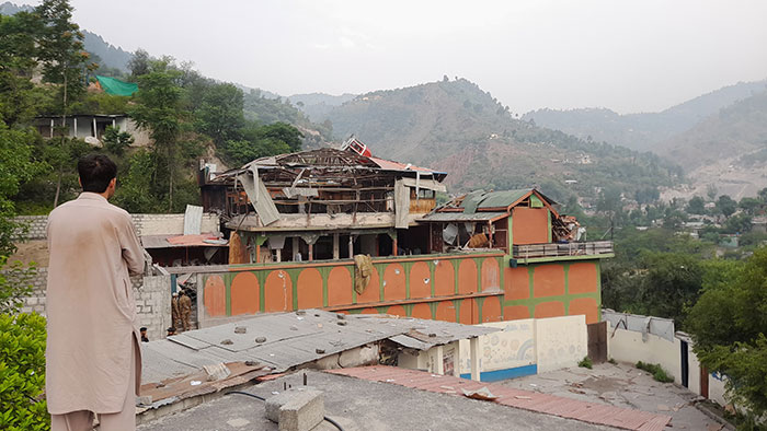 Man in traditional clothing observes damaged buildings after India bombs Pakistan, raising fears of war between nuclear-armed rivals