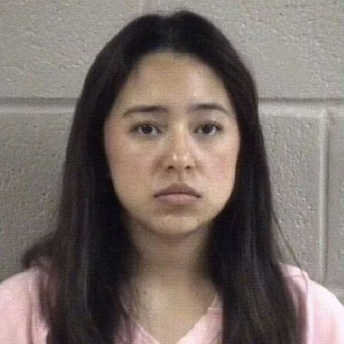 Mugshot of a college student facing deportation after making an illegal turn at a red light, wearing a pink shirt.
