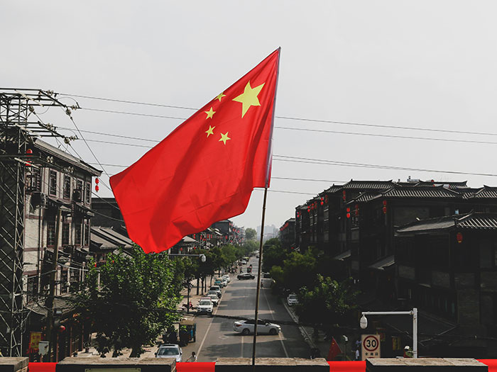 Chinese flag waving over a city street symbolizing U.S. and China trade deal to cut tariffs, officials report.