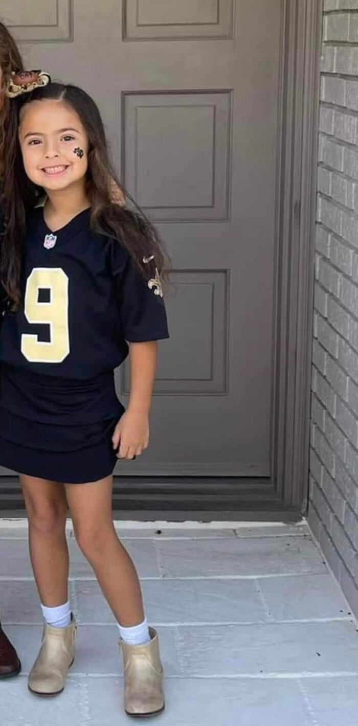Young girl smiling in a sports jersey standing outside a house, related to Louisiana woman kills boyfriend&rsquo;s daughter case.