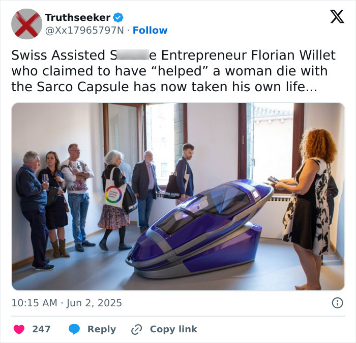 Visitors observe a sleek Sarco pod displayed indoors, relating to assisted suicide and Sarco pod advocacy.