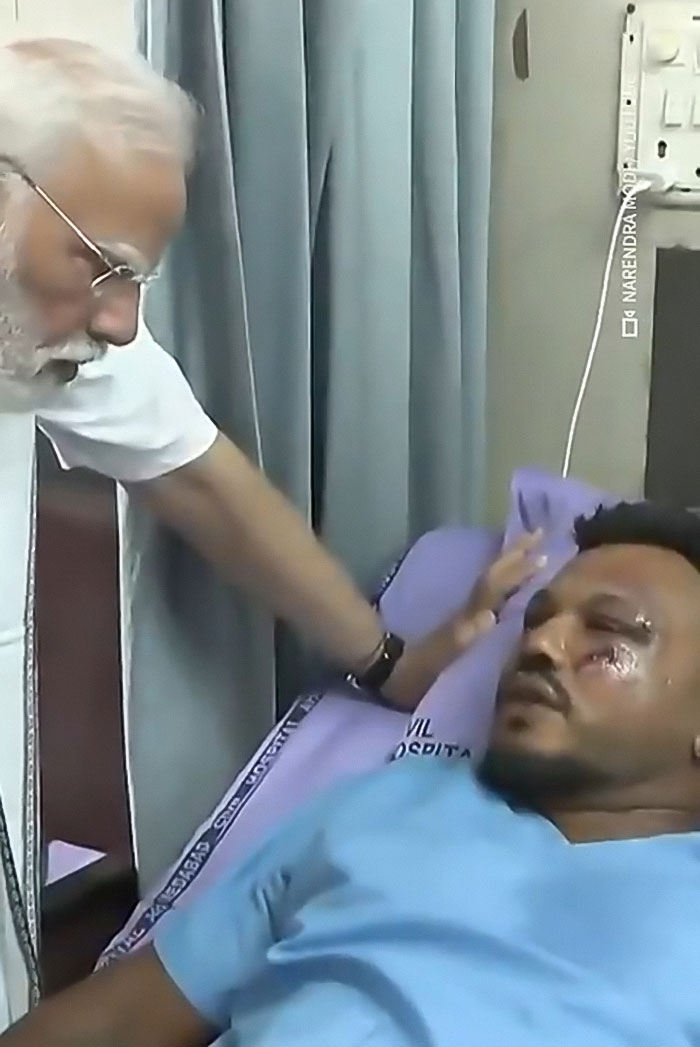 Indian leader visiting the lone survivor of the Air India crash lying in a hospital bed with visible injuries.