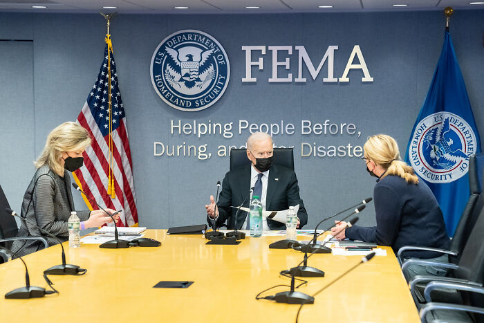FEMA chief and staff wearing masks in a meeting room under Department of Homeland Security during hurricane season preparation.