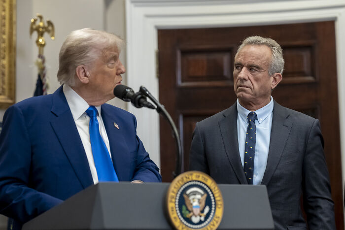 Robert F. Kennedy Jr. speaking at a podium with presidential seal during a public event in an official setting.