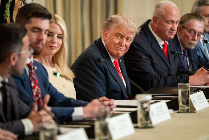 Donald Trump seated with advisors at a conference table discussing Appeals Court ruling on National Guard control in California.