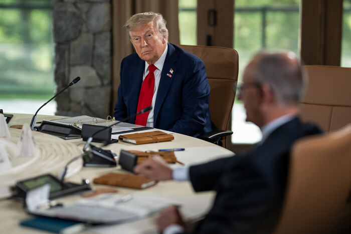 Donald Trump seated at a conference table in discussion, amid White House talks on Juneteenth and holiday policies.