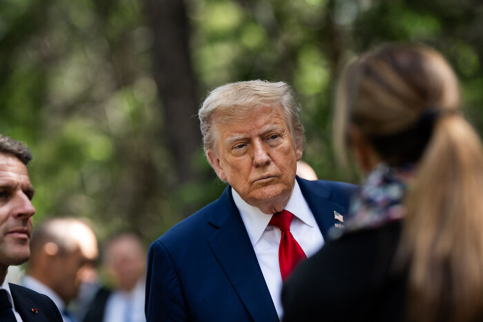 Former President Donald Trump outdoors in a suit and red tie, in a serious conversation, unrelated to Los Angeles Dodgers denied ICE entry.