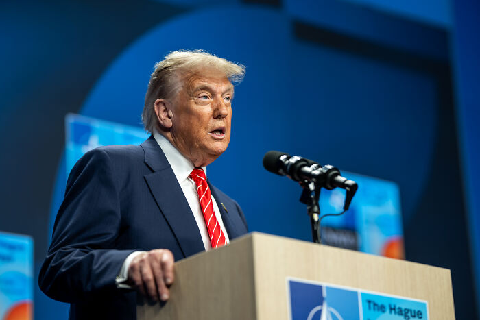 Former U.S. president speaking at a podium with microphones during a formal event on international relations.