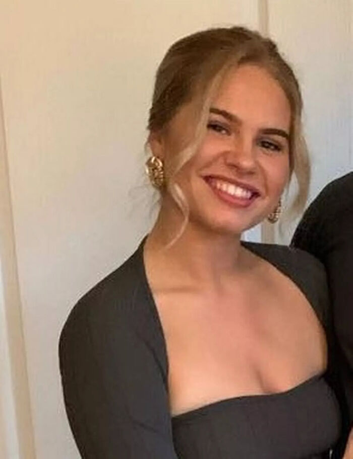 Young woman smiling indoors, with blonde hair and gold earrings, unrelated to man who accessed porn 170 times keyword.