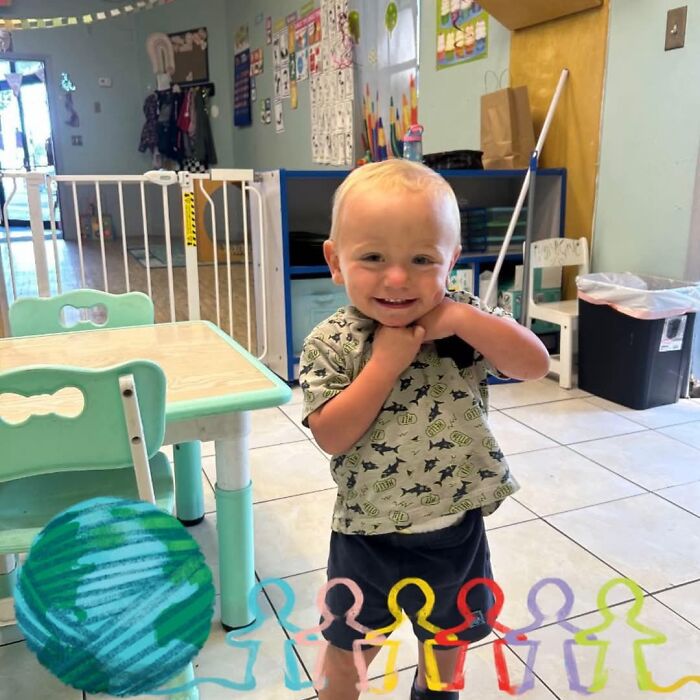 Toddler boy smiling in a playroom with colorful child figures and globe illustration, related to Florida car heat tragedy.