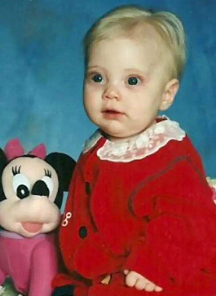 Toddler in a red outfit sitting next to a Minnie Mouse plush toy, related to killer dad case and medical examiner findings.