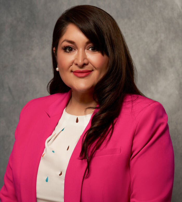 Woman in a bright pink blazer and white blouse posing for a professional portrait related to California official and ICE raids.