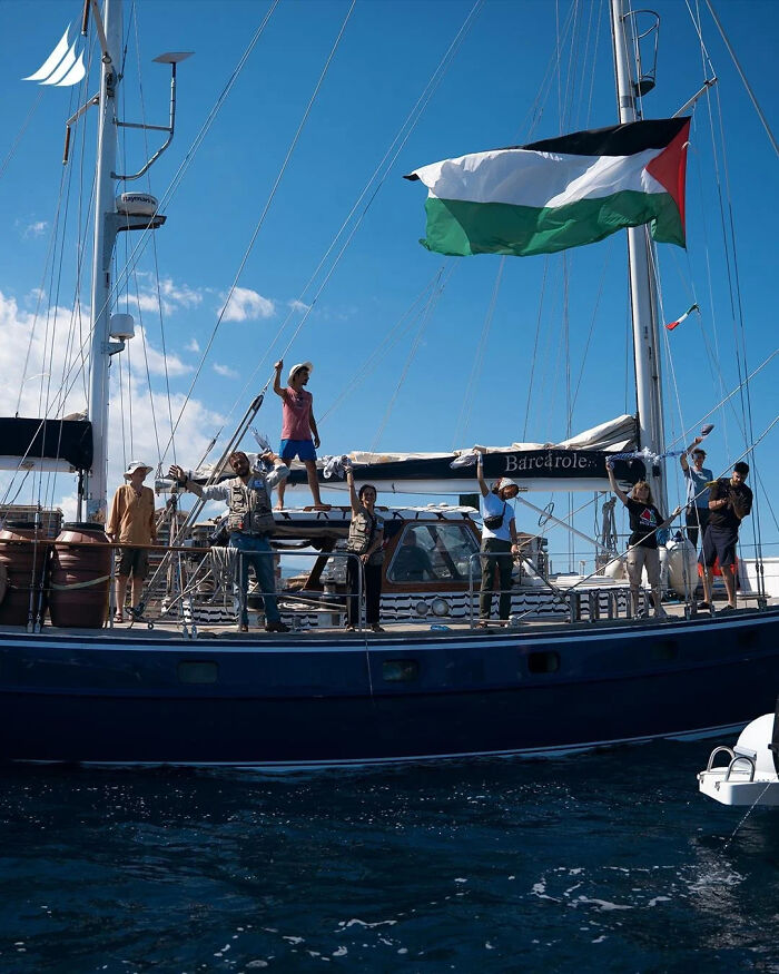 Activists on a Gaza-bound freedom flotilla boat flying the Palestinian flag amid interception by Israel at sea.