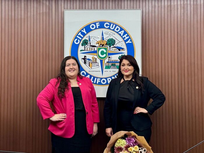 Two women standing in front of the City of Cudahy California seal, related to California official and ICE raids response.