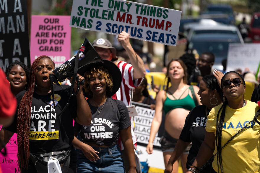 Protesters marching with signs against abortion bans, highlighting Georgia abortion ban and pregnancy rights issues.