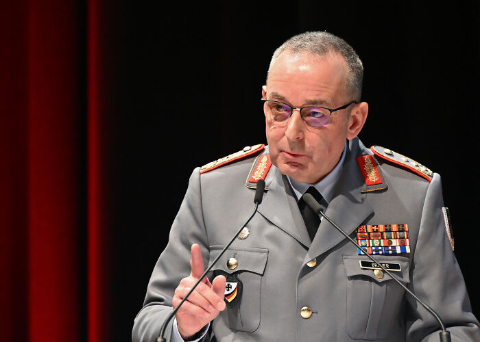 German official in military uniform speaking at a podium warning Putin may strike NATO amid rising tensions.