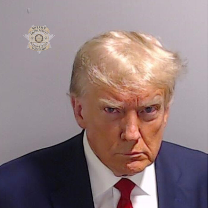 Mugshot portrait of Donald Trump wearing a dark suit and red tie, featured in the White House new Trump portrait reveal.