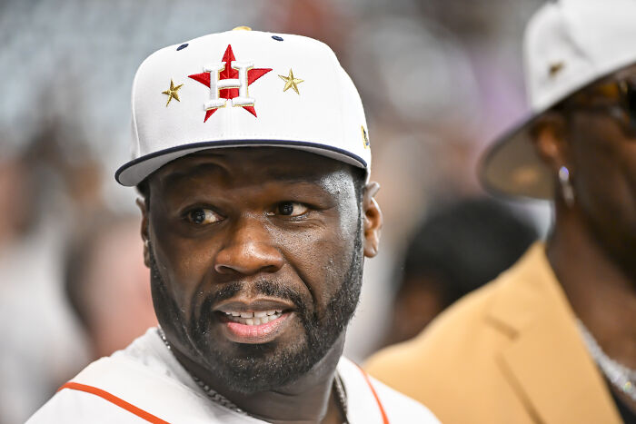50 Cent wearing a white Houston Astros cap, speaking at an event related to NYC mayoral candidate Zohran Mamdani tax plan.