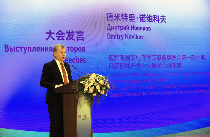 Russian official Dmitry Novikov speaking at a podium during a conference amid Russia Elon Musk political asylum talks.