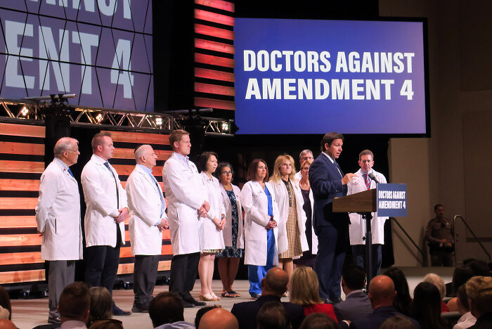 Group of doctors in white coats at a podium speaking against amendment 4, related to Florida GOP abortion law delay.