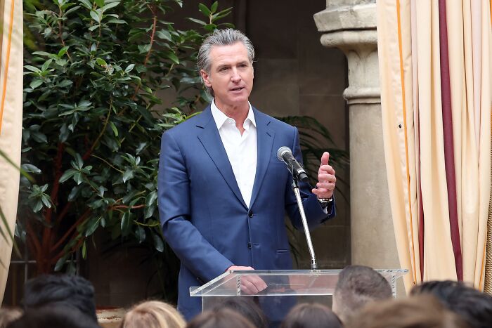 Governor Gavin Newsom speaking at a podium during a public event on military crackdown in Los Angeles.