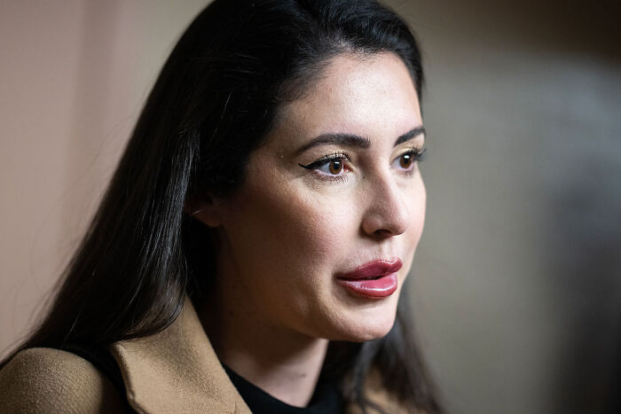 Young woman in a brown coat speaking about GOP proposals related to presidential fandom and political enthusiasm.