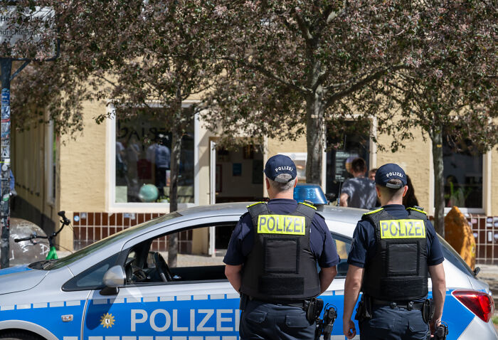 Two police officers stand near a vehicle outside a school amid reports of multiple children injured after tear gas attack.