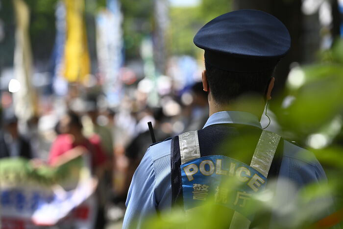 A Japanese police officer monitoring a crowd, related to Japan executes Twitter killer for murdering 9 victims.