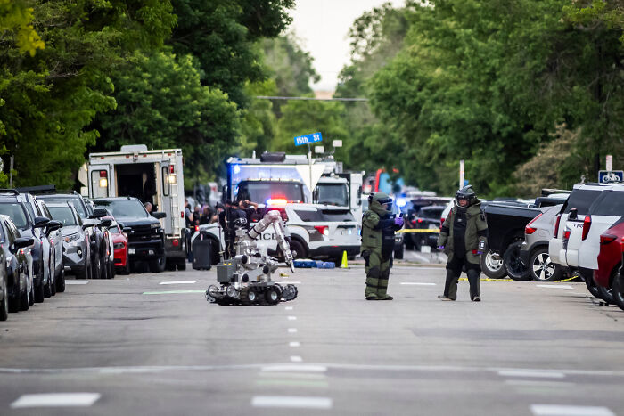 Police bomb squad and robot investigating flamethrower attack at peaceful protest for Israeli hostages in Colorado street.