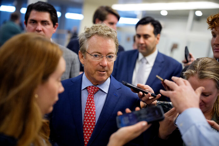 GOP senator speaking to reporters, wearing glasses and a suit, discussing Trump&rsquo;s armed forces parade and North Korea comparison.