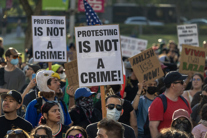 Protesters in a crowded demonstration holding signs against ICE amid Florida sheriff&rsquo;s vow of deadly force on violent protestors.