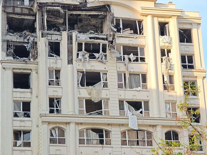Damaged multi-story building with broken windows and debris after Iran fires drones in strikes near Israel.