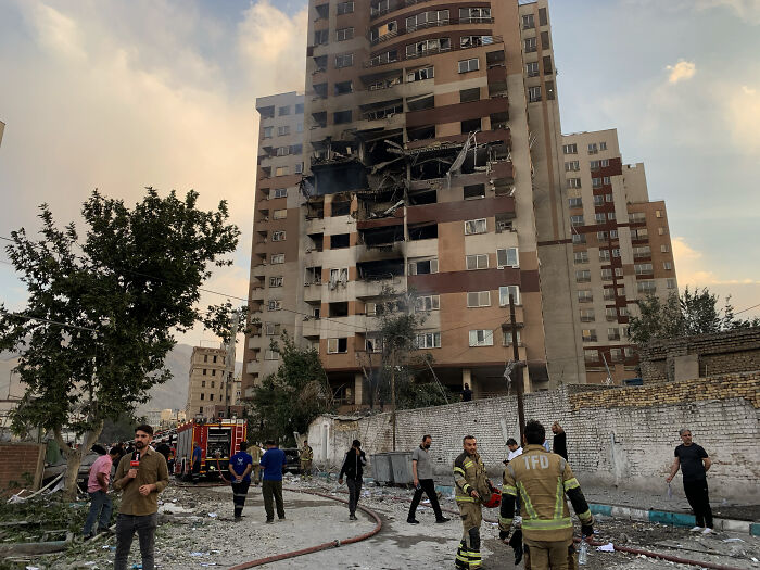 Damaged residential building after drone strikes in Israel with emergency responders at the scene following Iranian drone attacks.