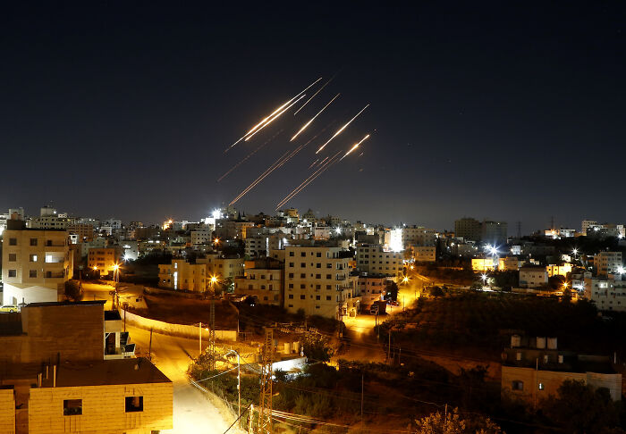 Nighttime view of U.S. strikes over cityscape with bright trails raising doubts on success of Iran sites attack.