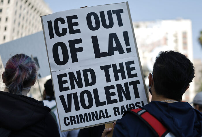 Protesters in California holding signs opposing ICE raids and urging an end to violent criminal actions in Los Angeles.