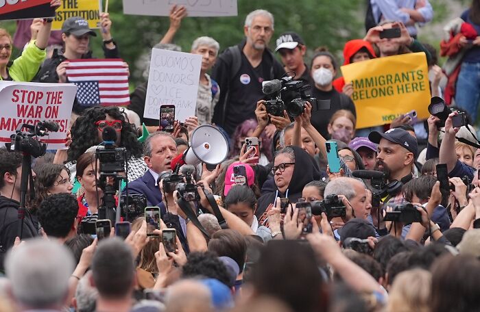 Crowd gathered as Brad Lander speaks through megaphone at protest supporting immigrants against ICE actions.