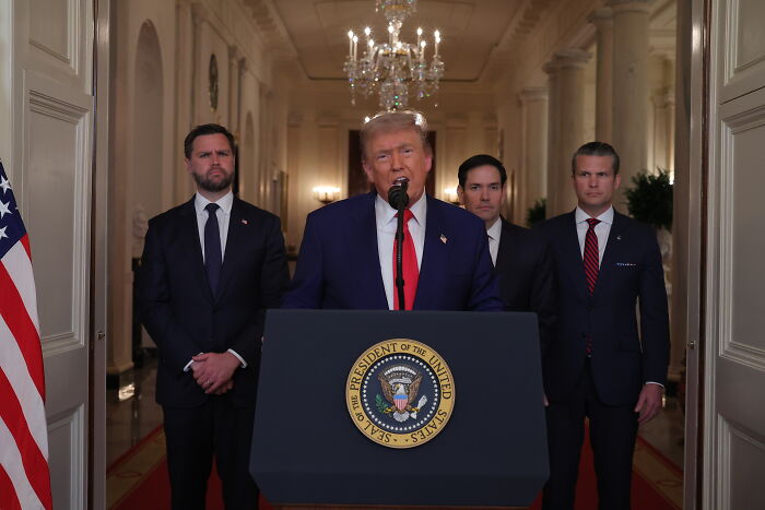 Former President Trump at podium with presidential seal, flanked by officials, addressing U.S. nuclear strike retaliation by Iran.