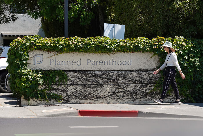 Woman walking past Planned Parenthood building with greenery, related to South Carolina cutting Medicaid funds Supreme Court ruling.
