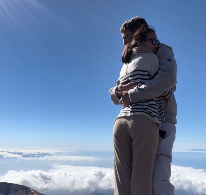 Couple embracing on a mountaintop with clouds below, symbolizing resilience amid October 7 hostage and terror sympathizers conflict.