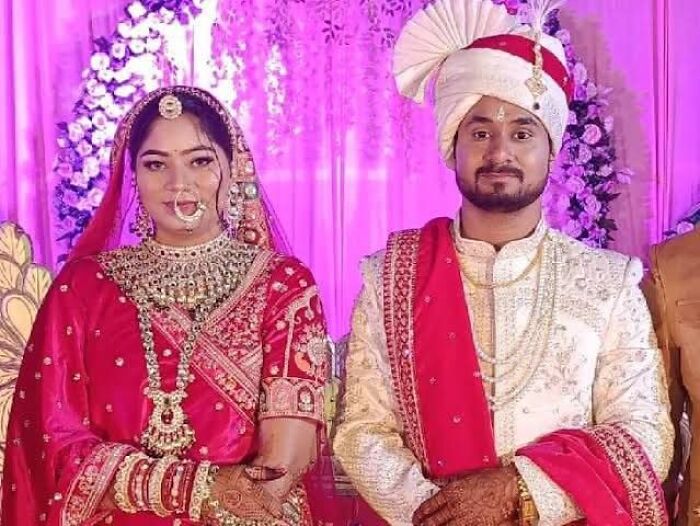 Bride and groom in traditional wedding attire with elaborate jewelry and decorations at a colorful wedding ceremony.