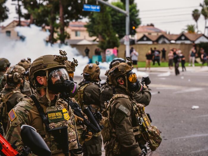 Heavily armed cops in tactical gear during LA riots amid deployment of National Guard and rubber bullet use on reporter.