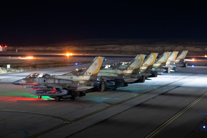 Row of fighter jets on a runway at night, illustrating Iran fires 100 drones at Israel amid military tensions.