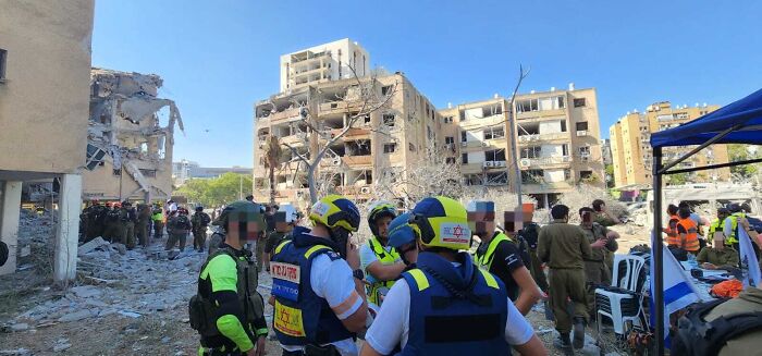 Emergency responders and military personnel at rubble site after attack, highlighting tensions involving Trump and Iran conflict plans.