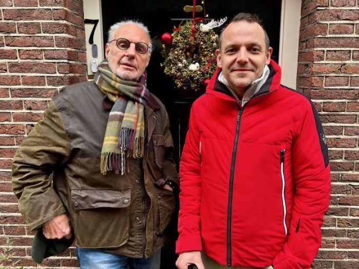 Two men standing outside a brick building, related to Sarco pod advocate and capsule death incident.